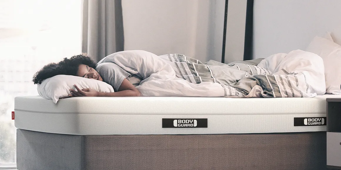 Photo: A person lies covered under a duvet in 155x220 bed linen on a BODYGUARD mattress
